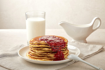 Sweet homemade stack of pancakes with jam and maple syrup for Breakfast with milk