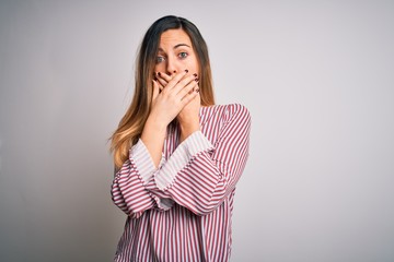 Young beautiful blonde woman with blue eyes wearing stiped t-shirt over white background shocked...