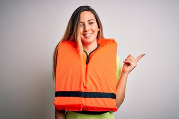 Young beautiful blonde woman with blue eyes wearing orange lifejacket over white background with a...