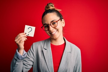 Young beautiful blonde woman with blue eyes holding reminder paper with question mark with a happy face standing and smiling with a confident smile showing teeth