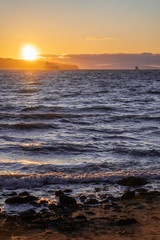 sunset on beach with rocks in the front and cargo boat on water pacific ocean Pacific north west PNW Vancouver Canada boats waiting vertical photo 