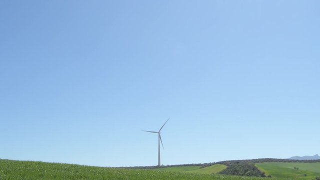 Wind turbine moving the blades in a field a sunny day with blue sky