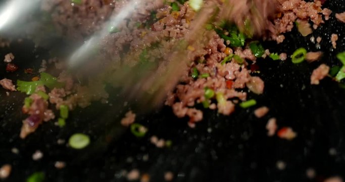 Close up view stir and cook minced pork with dry chilli powder and spring onion to make Larb, Thai Spicy minced pork salad.