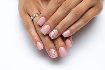 Close-up of pink manicure with a painted white feather on short square nails on a white background. Nude manicure. Beige, Body, Natural nails.