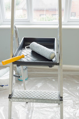 Painting and decorating supplies with cans of paint and a dust sheet in the background