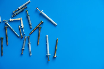 Many different nails screws nuts bolts on blue background of the copy space. Construction and repair concept