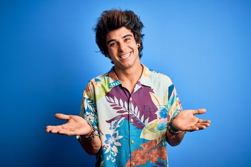 Young handsome man on vacation wearing summer shirt over isolated blue background clueless and...