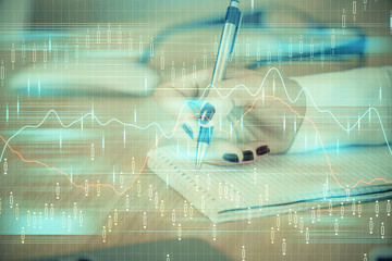 Multi exposure of hands making notes with forex chart huds. Stock market concept.
