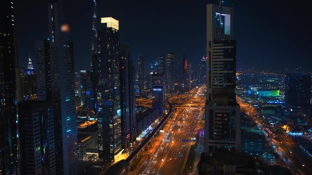 Modern skyscrapers, illuminated roads at night in luxury downtown of Dubai city skyline, UAE. View from above from rooftop