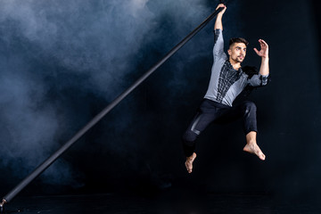 Performance concept. Man hanging on chinese pole. Athlete performing flying pole