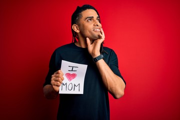 Young african american man holding love mom message paper celebrating mothers day serious face...