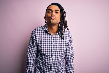 Young handsome african american afro man with dreadlocks wearing casual shirt looking at the camera blowing a kiss on air being lovely and sexy. Love expression.
