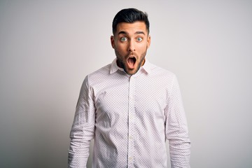 Obraz premium Young handsome man wearing elegant shirt standing over isolated white background afraid and shocked with surprise and amazed expression, fear and excited face.