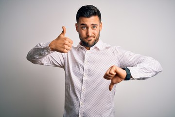 Young handsome man wearing elegant shirt standing over isolated white background Doing thumbs up and down, disagreement and agreement expression. Crazy conflict