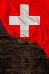 vertical colored national flag of modern state of Switzerland, beautiful silk, old wood background, concept of tourism, economy, politics, emigration, independence day, copy space, template