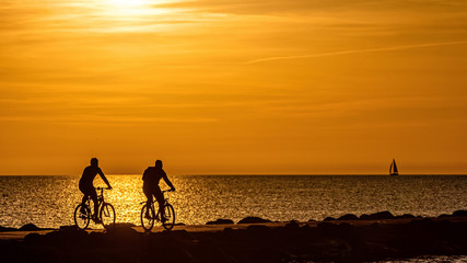 Fototapeta na wymiar silhouette of people biking on the pier during the golden hour of sunset