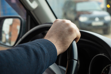 Man's hand holding the steering wheel of a car close-up