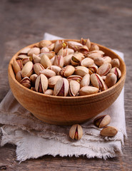 Pistachios in a wooden bowl on a dark background