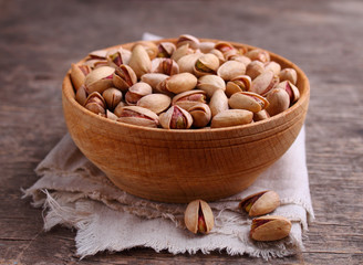 Pistachios in a wooden bowl on a dark background