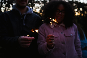 Group of young friends at the park at sunset watch the smart phones sitting on a bench - Five people have fun together