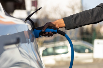 African American person plugin her EV electric car at the charging station