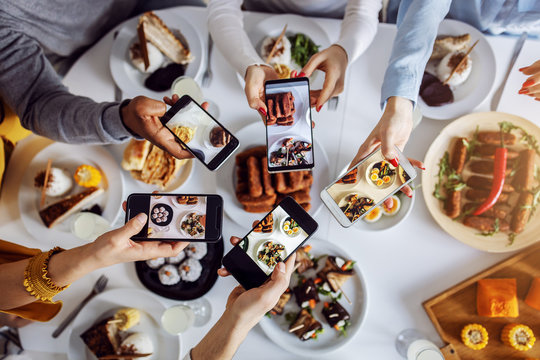 Top view of group of multicultural friends taking photos with smart phones for of healthy food they having for lunch. They gonna post it on social media.