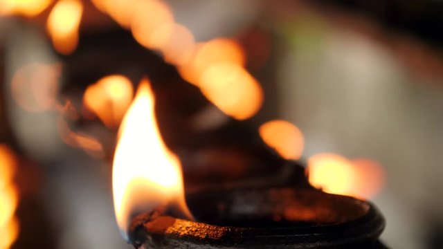 Closeup 4k video of long row of burning oil lamps with sacred fire at hindu temple