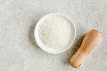 Salt in a bowl with scoop on gray stone table. Sea salt flat lay, top view. Spa skincare concept. Natural/Organic spa cosmetics products