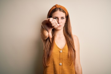 Young beautiful redhead woman wearing casual t-shirt and diadem over yellow background looking...