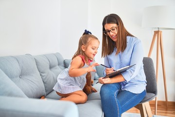 Young therapist woman speaking and treating child, counselor and behaviour correction at pedagogue payroom taking notes on clipboard