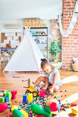 Young beautiful blonde girl kid enjoying play school with toys at kindergarten, smiling happy playing with building blocks at home