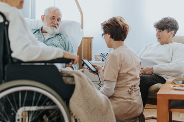 Helpful nurse switching on a professional bed in a nursing home