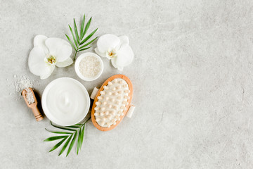Fototapeta na wymiar Spa treatment concept. Natural/Organic spa cosmetics products, massage brush and tropic palm leaves on gray marble table from above. Spa background, flat lay, top view.