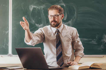 Young bearded professor in shirt and tie asking his students a question during seminar