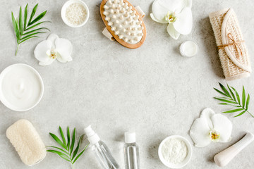 Naklejka na ściany i meble Spa treatment concept. Natural/Organic spa cosmetics products, sea salt, massage brush, tropic palm leaves on gray marble table from above. Spa background with a space for a text, flat lay, top view
