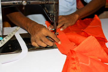 Close up image of Gents hands sewing her cloth with old sewing machine