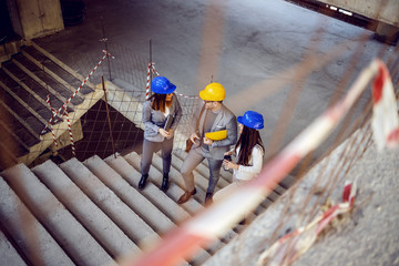 Group of successful young innovative architects climbing the stairs and talking about project....