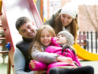Happy family of four at children's playground