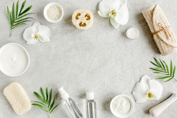 Obraz na płótnie Canvas Spa treatment concept. Natural/Organic spa cosmetics products, sea salt, massage brush, tropic palm leaves on gray marble table from above. Spa background with a space for a text, flat lay, top view