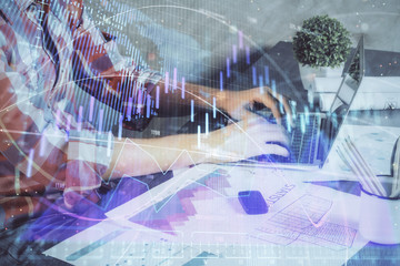 Double exposure of stock graph with businessman typing on computer in office on background. Concept...