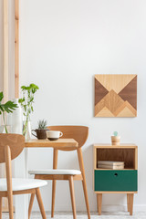 Green plants in small vases on long wooden dining table in bright interior