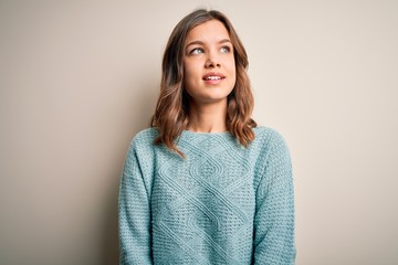 Fototapeta premium Young blonde girl wearing casual blue winter sweater over isolated background looking away to side with smile on face, natural expression. Laughing confident.