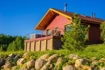 The cottage on the background of bright sky. Summer vacation in the country. The terrace has a hot tub and a sun lounger. SPA treatments in the fresh air. Relaxation. Recuperation.