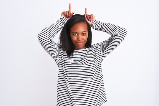 Beautiful young african american woman wearing winter sweater over isolated background doing funny gesture with finger over head as bull horns
