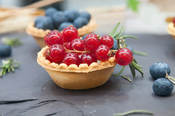 Tartlets with red currant and blueberries.Tartlet with berries on dark background.