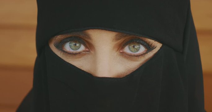 Portrait of a muslim woman wearing traditional black niqab showing only her green eyes, middle east culture