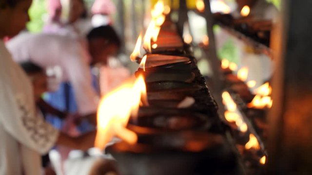 Closeup 4k video of burning oil lamps and worshipping religious people in altar at buddhist temple
