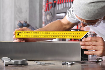 man work in home workshop garage measure metal with ruler angle square, on the workbench with wrenches and hammer, diy and craft concept