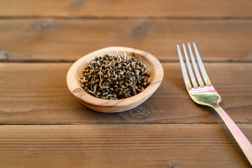 sprouted food hemp seeds in a wooden bowl and metal fork on a wooden background