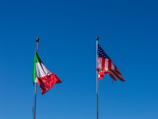 National flags of Italy and United States fluttering on background of blue sky